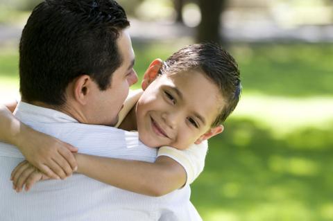 father and preschool age son hugging outdoors