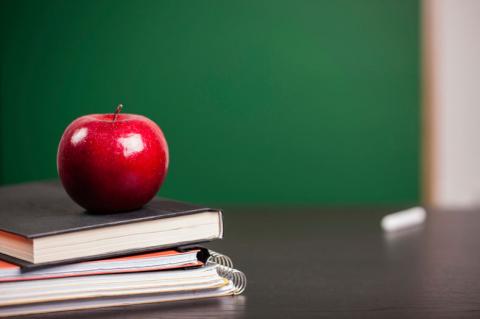 school textbooks and an apple on a desk