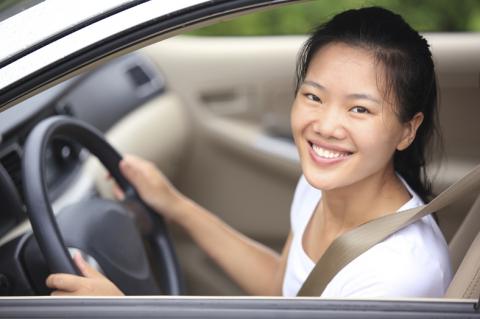 young adult woman driving and smiling