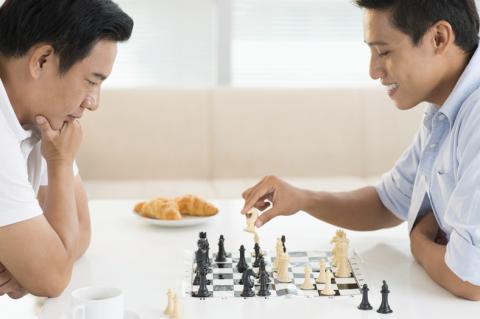 father and young adult son playing chess