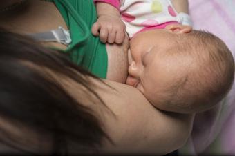 newborn baby feeding at mother's breast